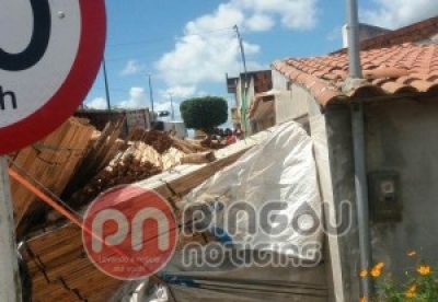 Glória: Carreta carregada de madeira tomba e parte da carga atinge residências (Foto: Reprodução/Pingou Notícias)