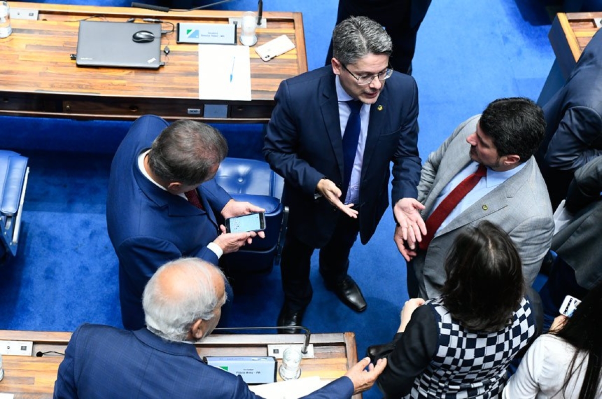 O relator do projeto, Alessandro Vieira (gravata azul), conversa no Plenário com Marcos do Val (gravata vermelha) e outros senadores (Foto: Marcos Oliveira/ Agência Senado)