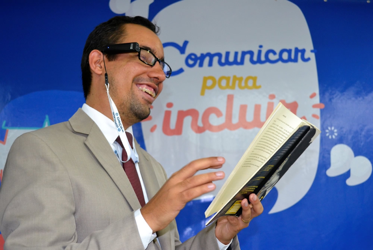 Lucas Aribé testa os óculos OrCam MyEye e faz leitura de um livro impresso em tinta (Foto: Assessoria Lucas Aribé)